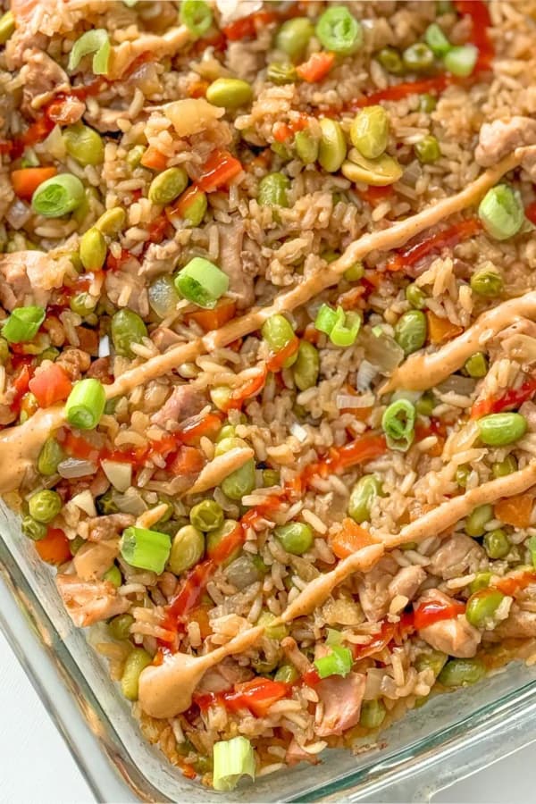 A chicken fried rice casserole drizzled with sriracha and spicy mayo.