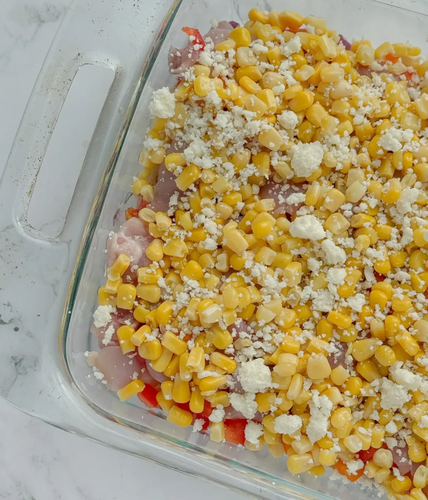 Adding corn and cotika cheese to the casserole dish.