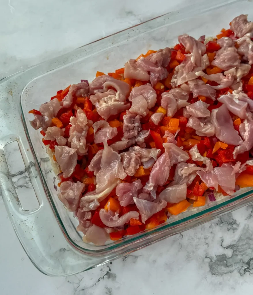 Assembling the one pan street corn casserole and adding raw chicken.