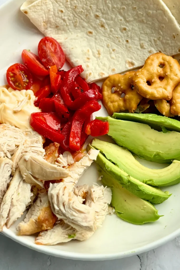A chicken, avocado, and veggie snack plate.