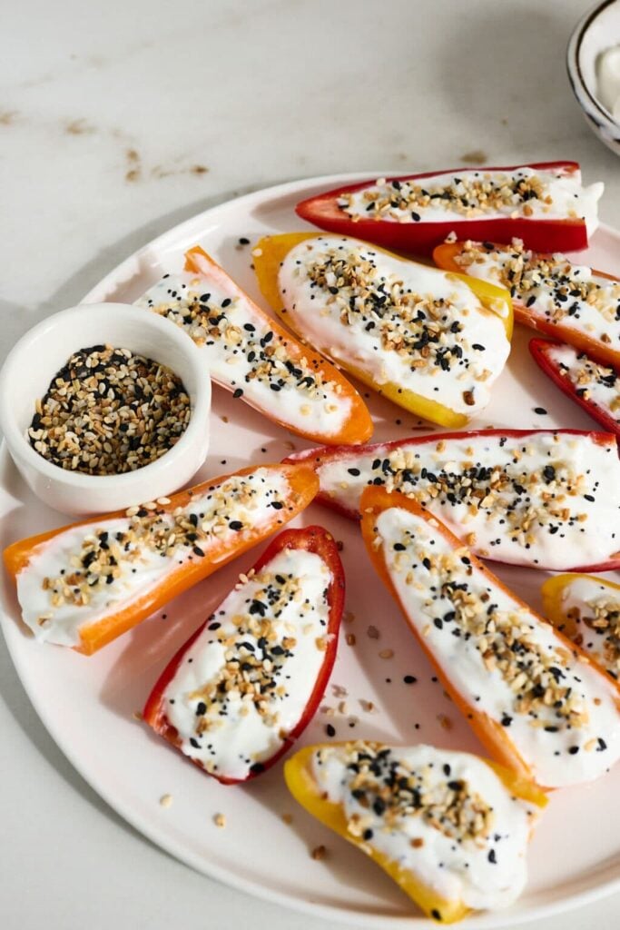 Stuffed mini sweet peppers on a white plate on a counter.