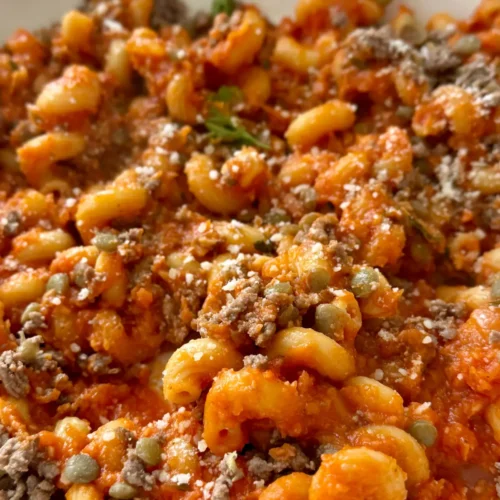 A bowl of pasta with ground meat in a white bowl.