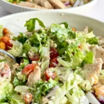 A close-up of a lazy chicken Caesar bowl combined with the dressing with a fork in it.