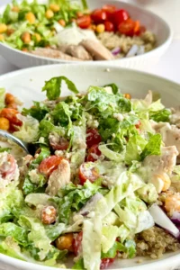 A close-up of a lazy chicken Caesar bowl combined with the dressing with a fork in it.