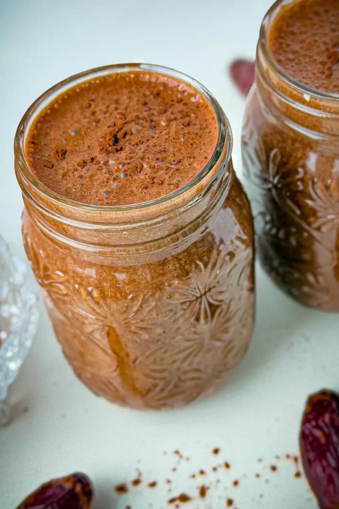 Two dark chocolate and peanut butter date smoothies in glasses.