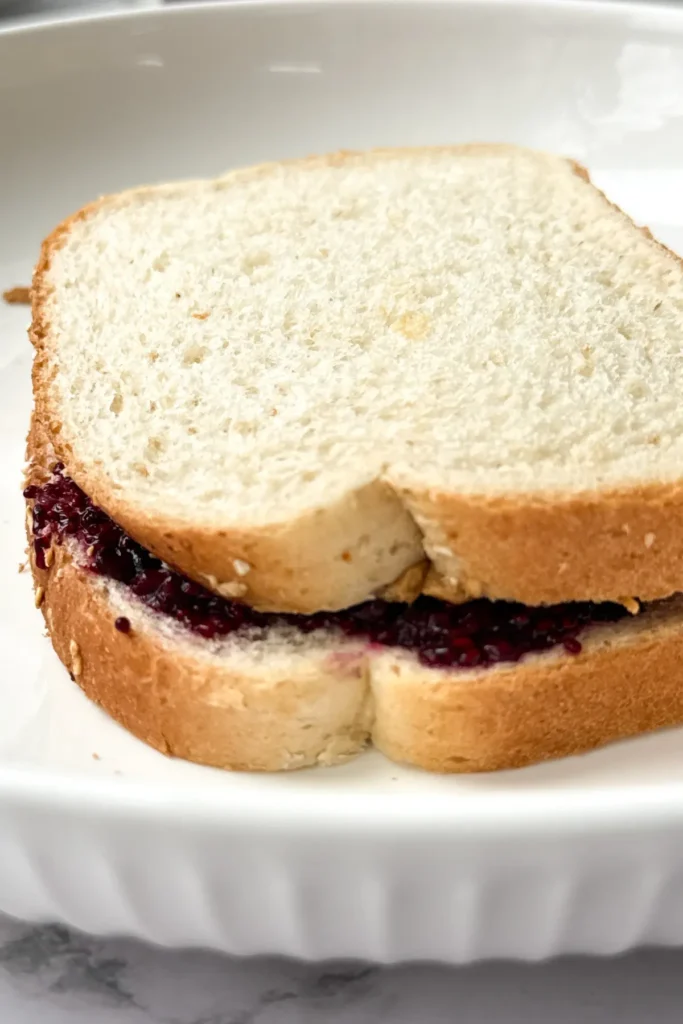 A peanut butter and chia jam sandwich close-up on a white plate.
