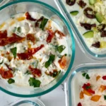 A birds-eye view of 5 cottage cheese dips in small snack containers on a counter.