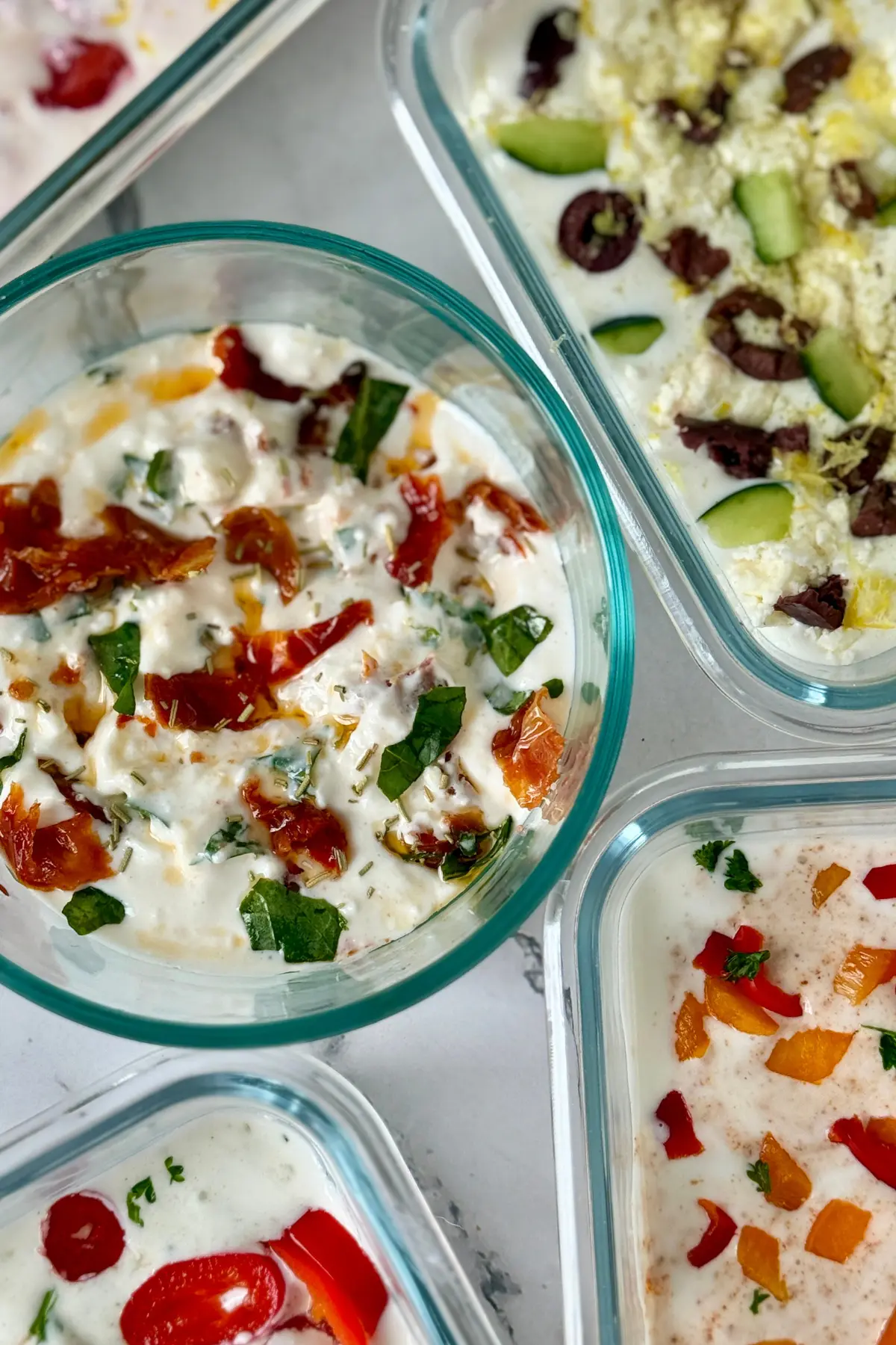A birds-eye view of 5 cottage cheese dips in small snack containers on a counter.
