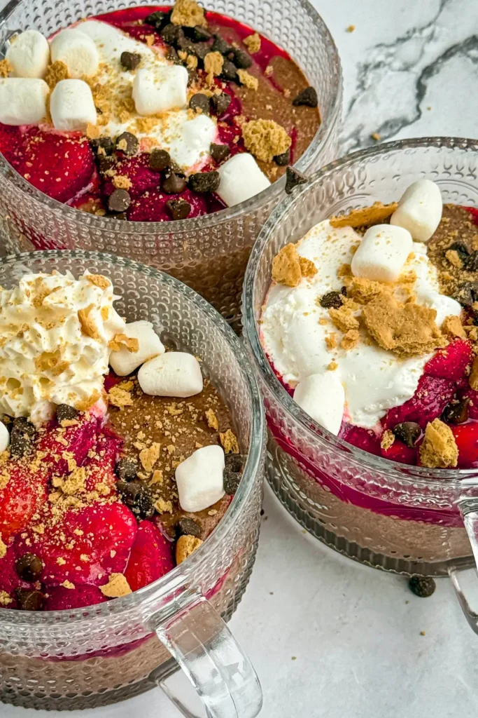 Three bowls of fully assembled high protein s'mores chia pudding on a table.