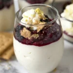 A close-up of a glass of whipped cottage cheese and cream cheese topped with berries and whipped cream.