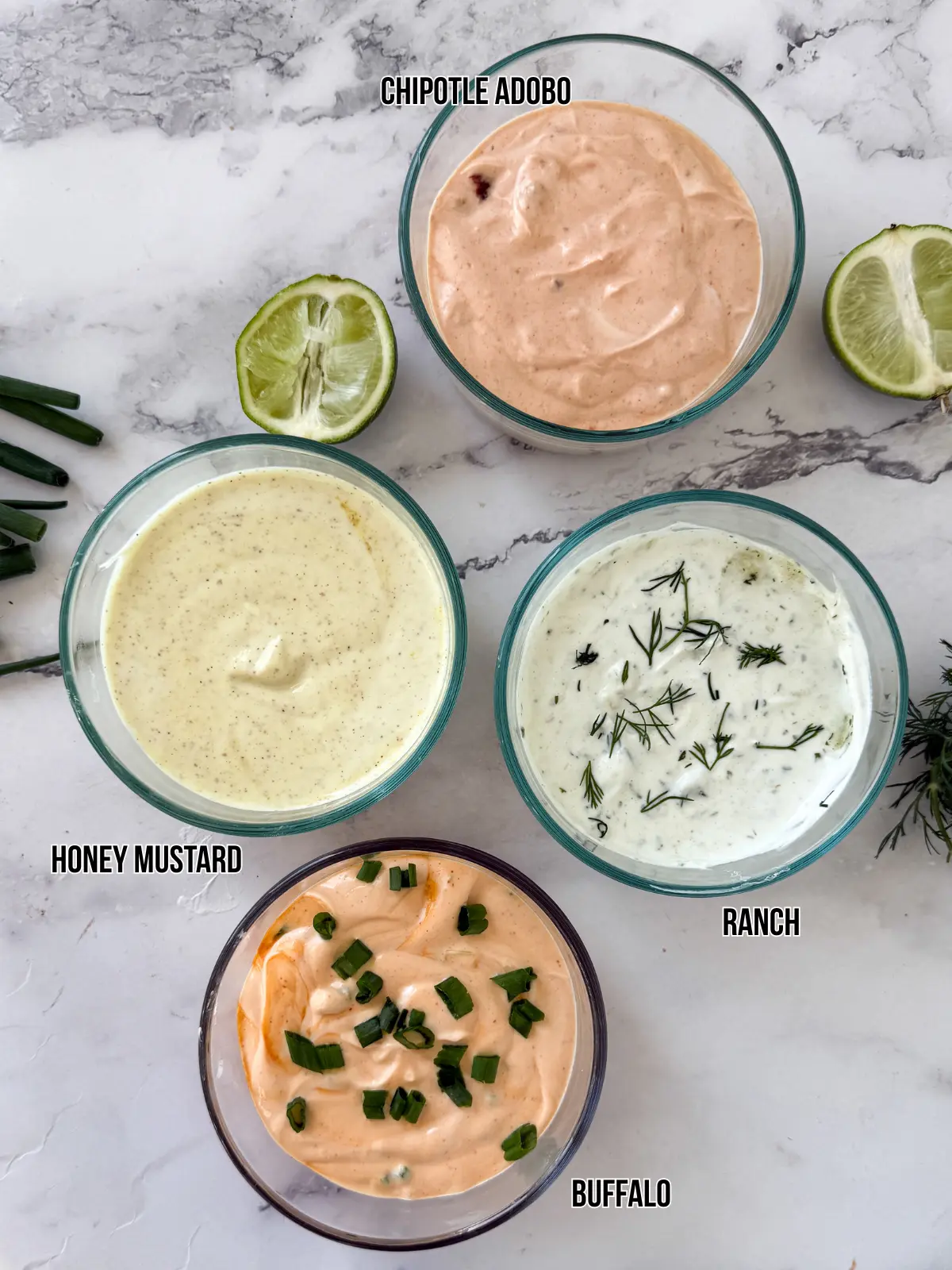 Four different Greek yogurt sauces in small glass containers on a counter.