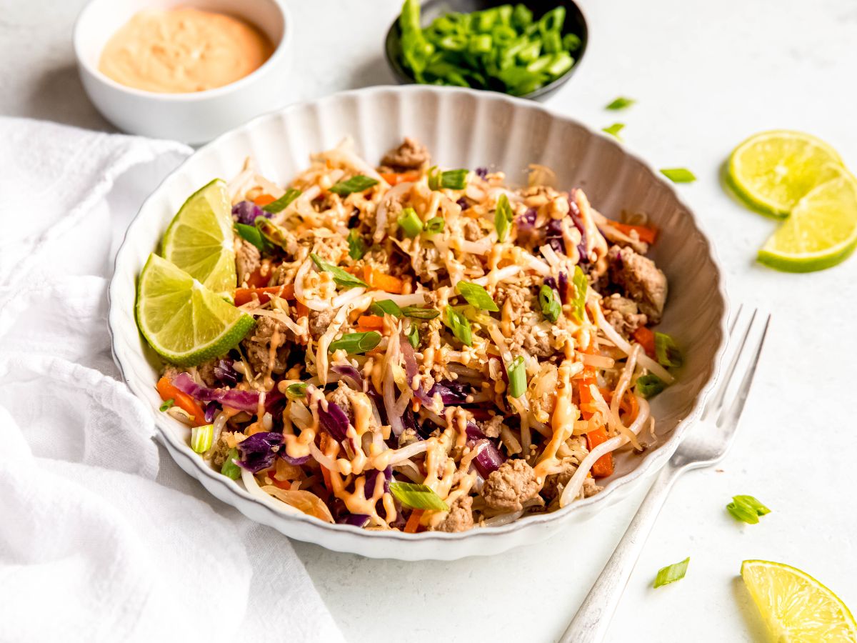 A big bowl of egg roll inspired stir-fry on a table next to a fork.