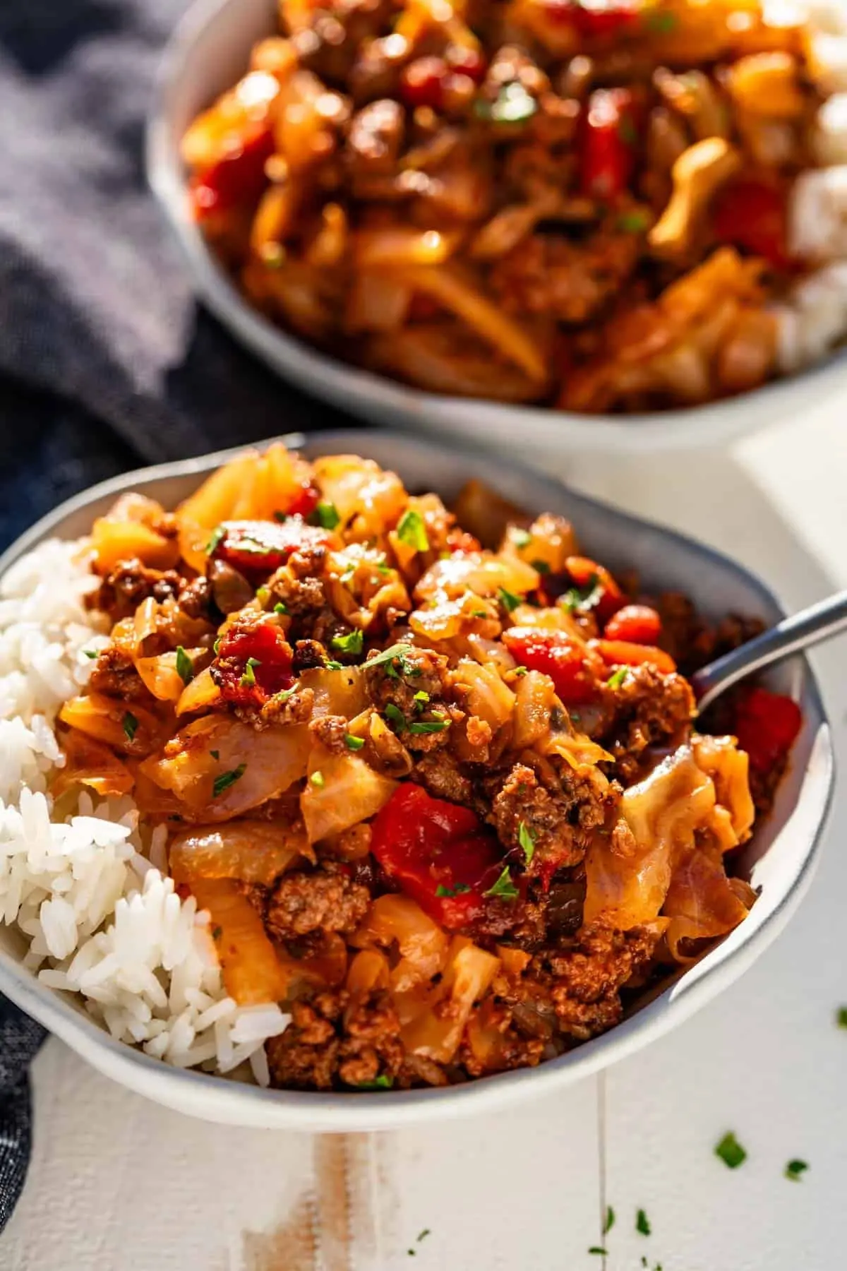 Two bowls of ground beef and cabbage with rice on a table.