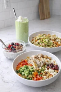 Three high fiber bowls on a counter next to a green smoothie in a kitchen.