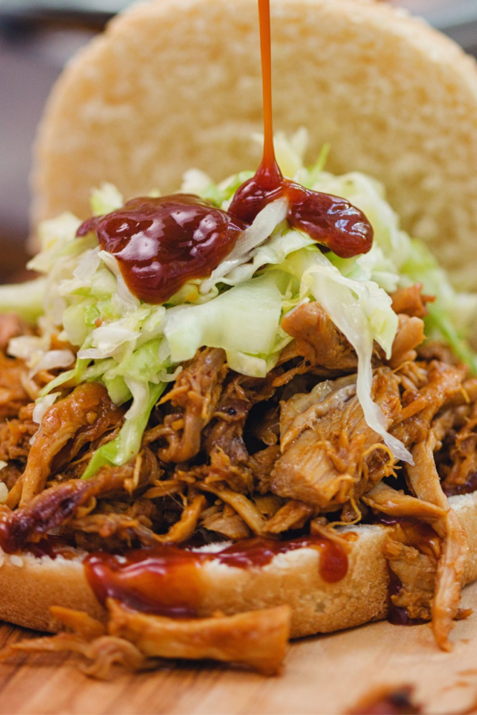 An open face pulled pork sandwich with slaw on a plate.