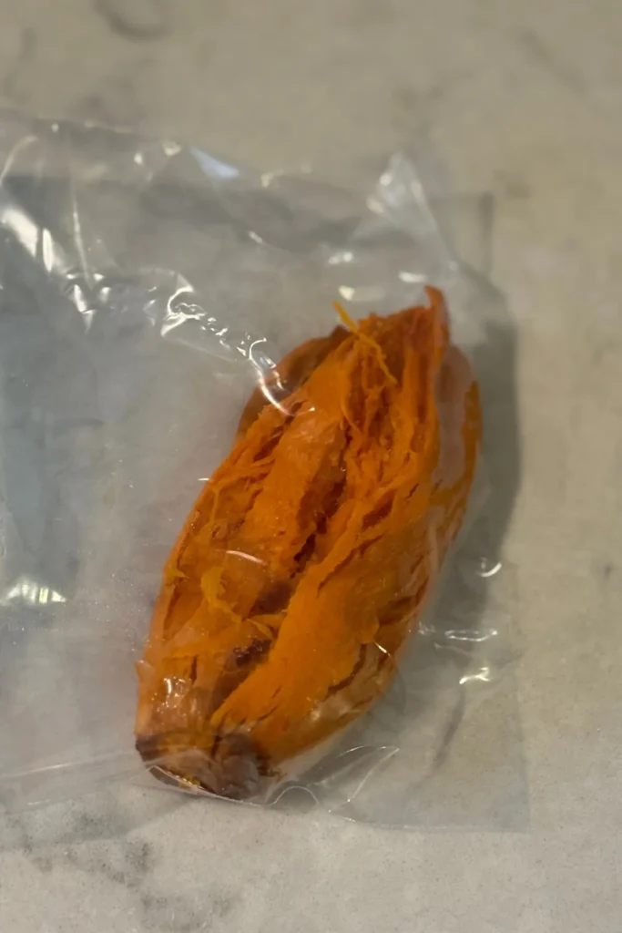 A baked sweet potato without the skin in a sandwich bag on a counter.
