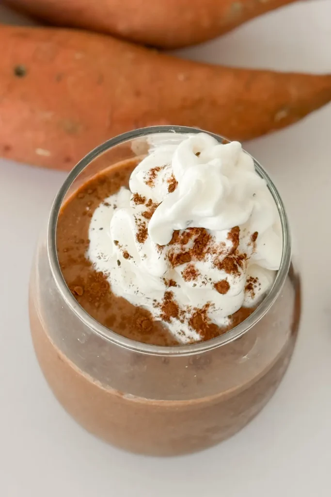 A birds-eye view of a glass of chocolate sweet potato smoothie topped with whipped cream.
