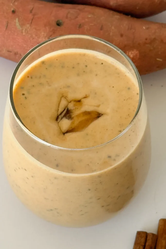 A creamy sweet potato pie smoothie with a drizzle of maple syrup on top.