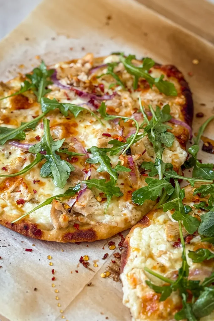 Two hot honey cottage cheese flatbreads with arugula on parchment paper after baking.