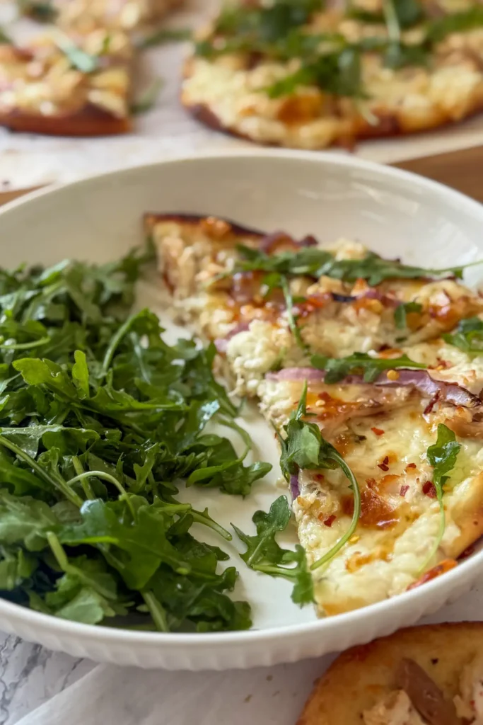 Two slices of cottage cheese and honey flatbreads on a plate with an arugula salad.