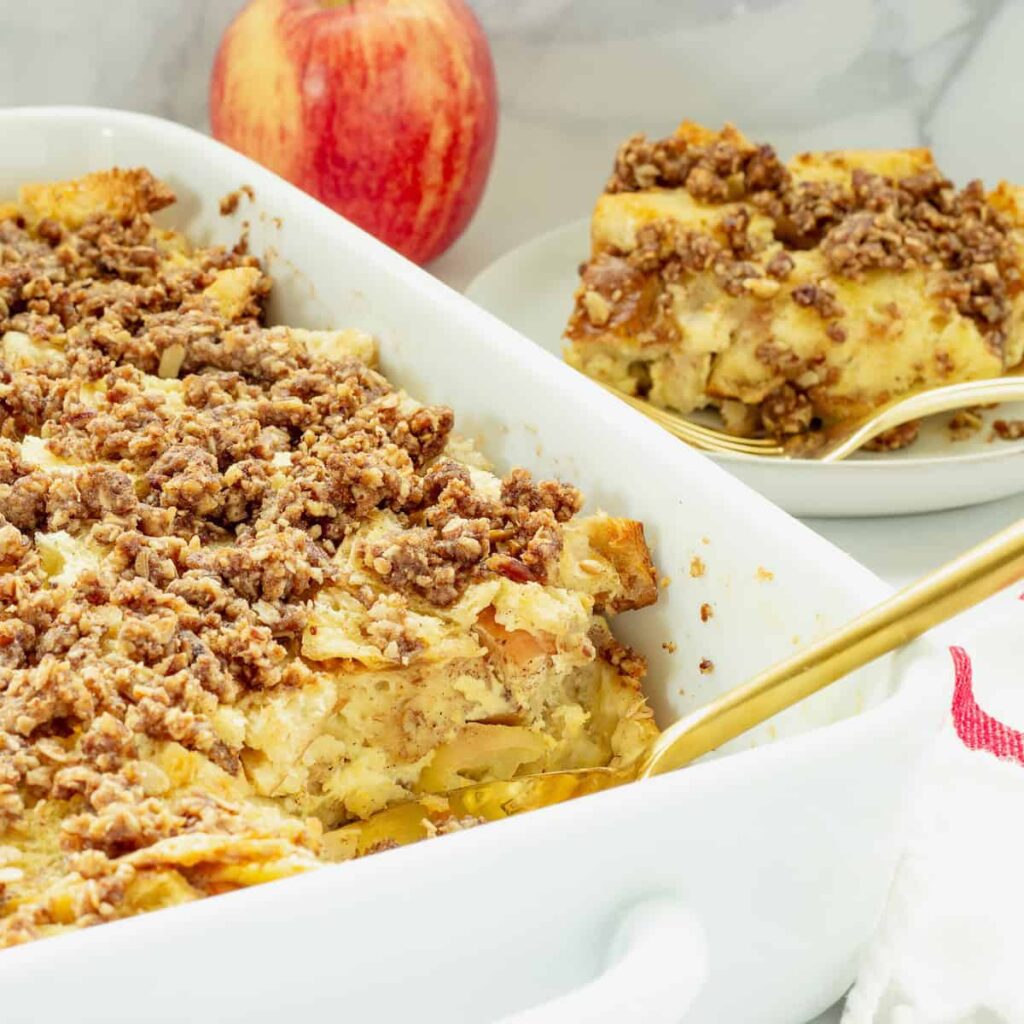 A baking dish of French toast casserole on a table next to a plate.
