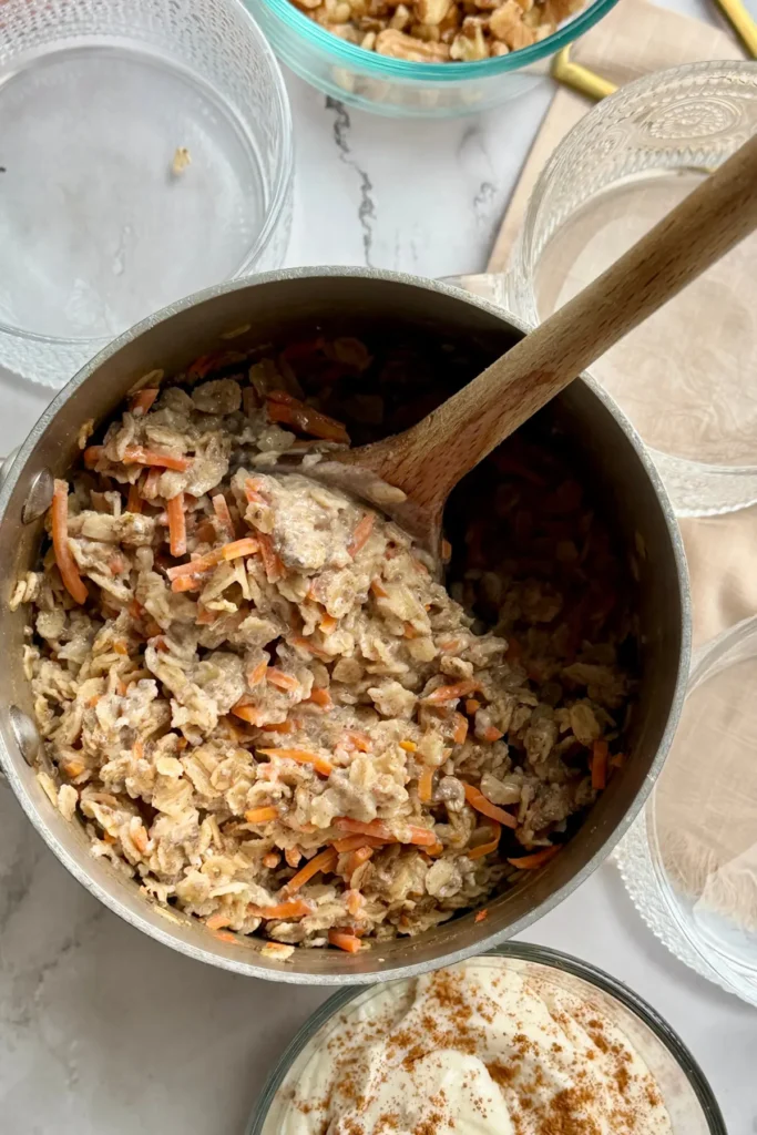 A birds-eye view of the cooked oatmeal in a pot with a wooden spoon in it.