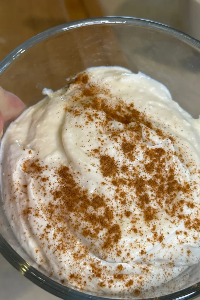 The Greek yogurt frosting sprinkled with cinnamon in a bowl.