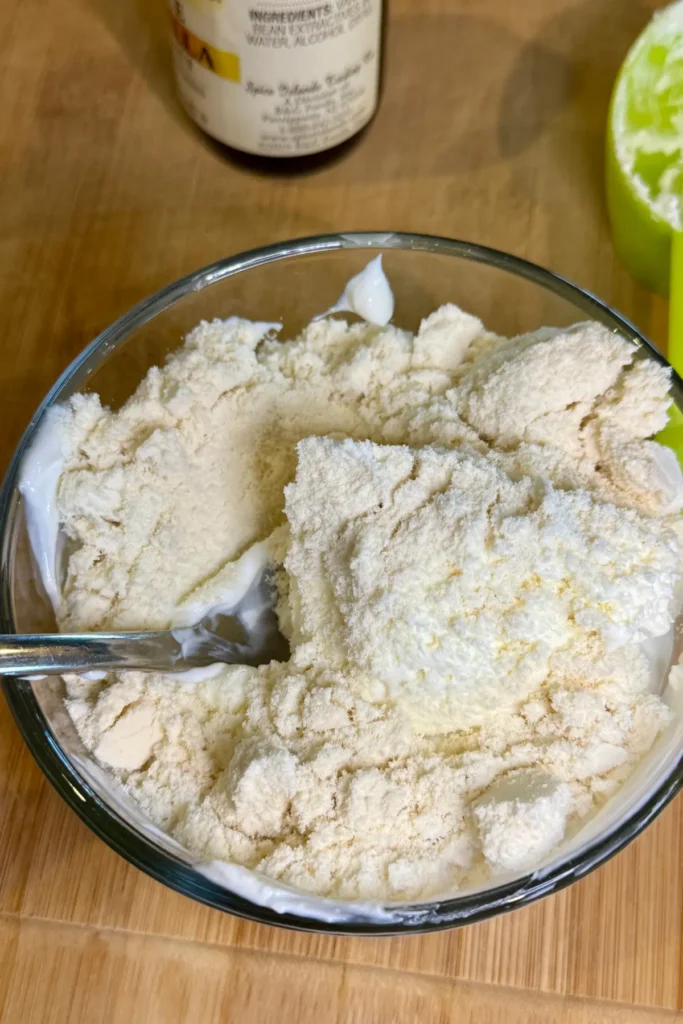 The ingredients for the Greek yogurt frosting in a bowl on a wooden cutting board.