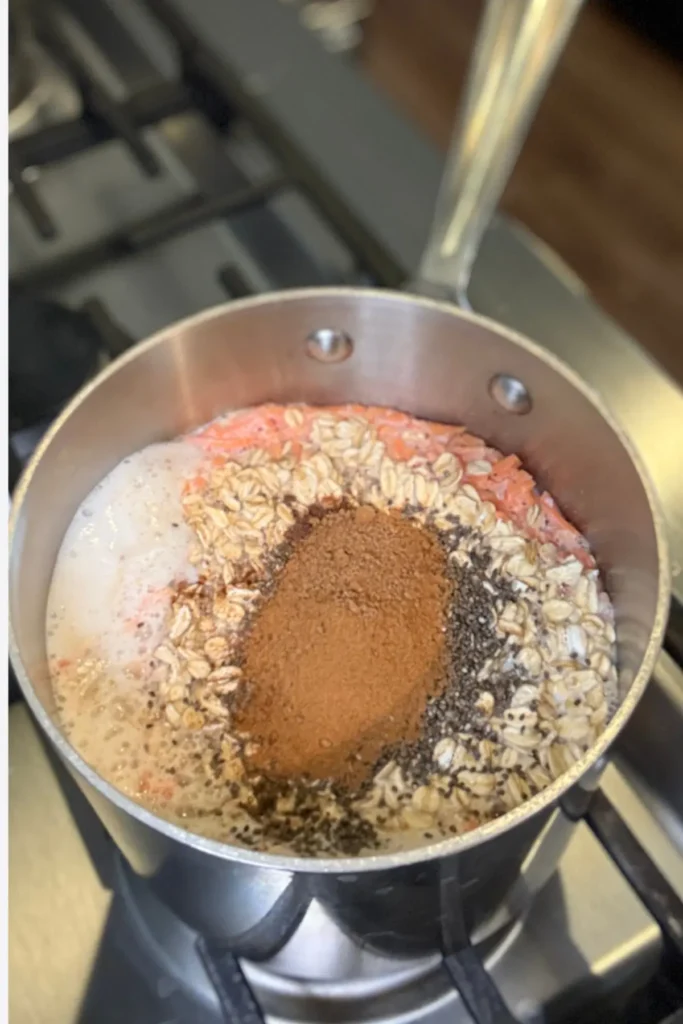 The oats, cinnamon, nutmeg, and chia seeds added to the hot pan of milk, water and carrots.