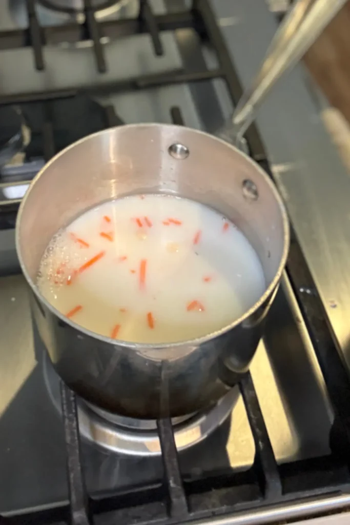 The milk, water and shredded carrots in a pan on medium heat.