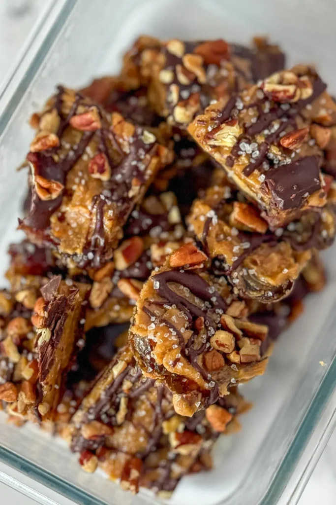 Maple pecan dates bars sliced and stacked in a glass storage container.