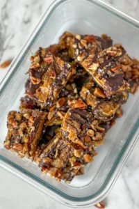 Sliced maple pecan date bars piled up in a glass container.
