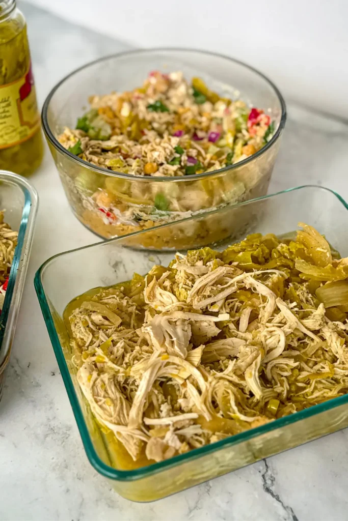 A birds-eye view of a slow cooker next to a power bowl with chicken and veggies and the chicken salad.