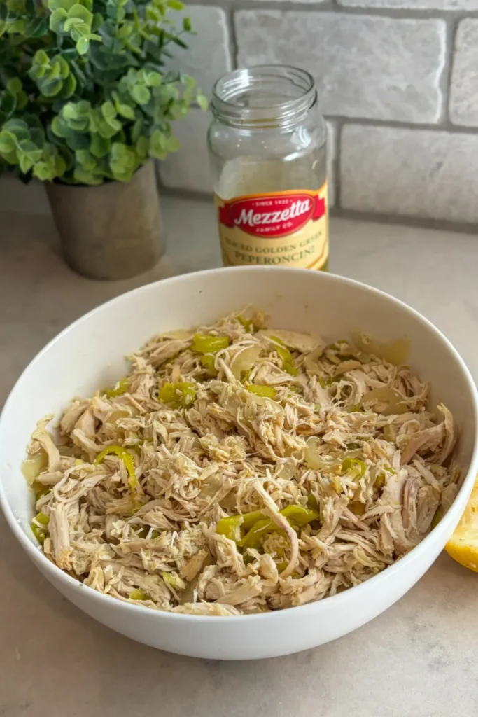 The shredded pepperoncini chicken and onions in a large white bowl. 