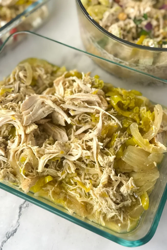 A birds-eye view of the leftover shredded chicken in a meal prep storage container.