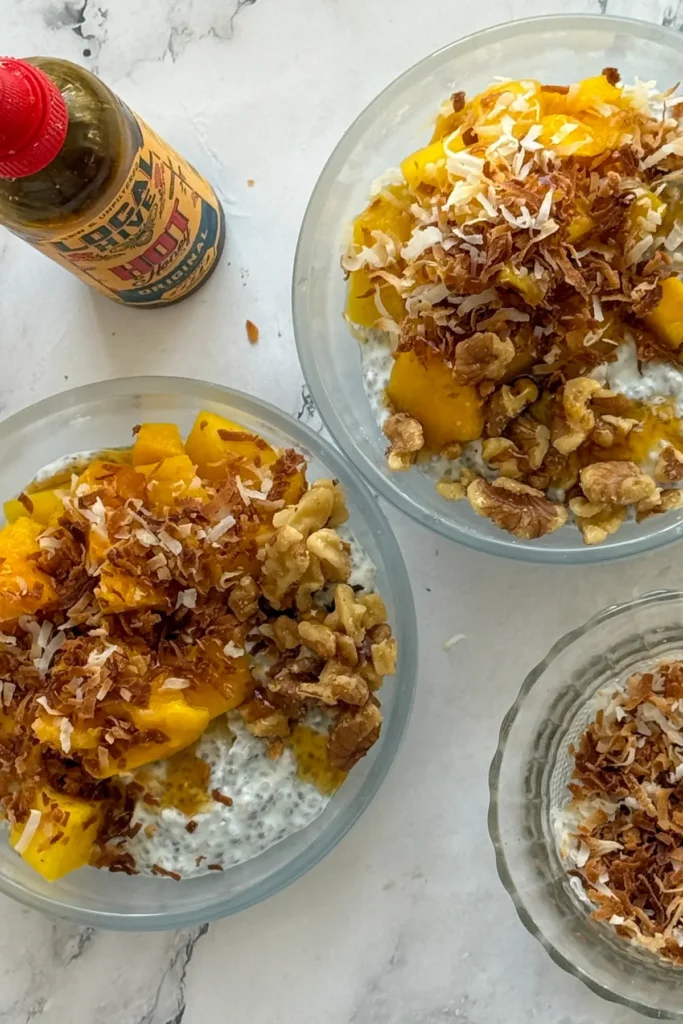 Two mango chia breakfast bowls topped with hot honey and shredded coconut on a counter. 