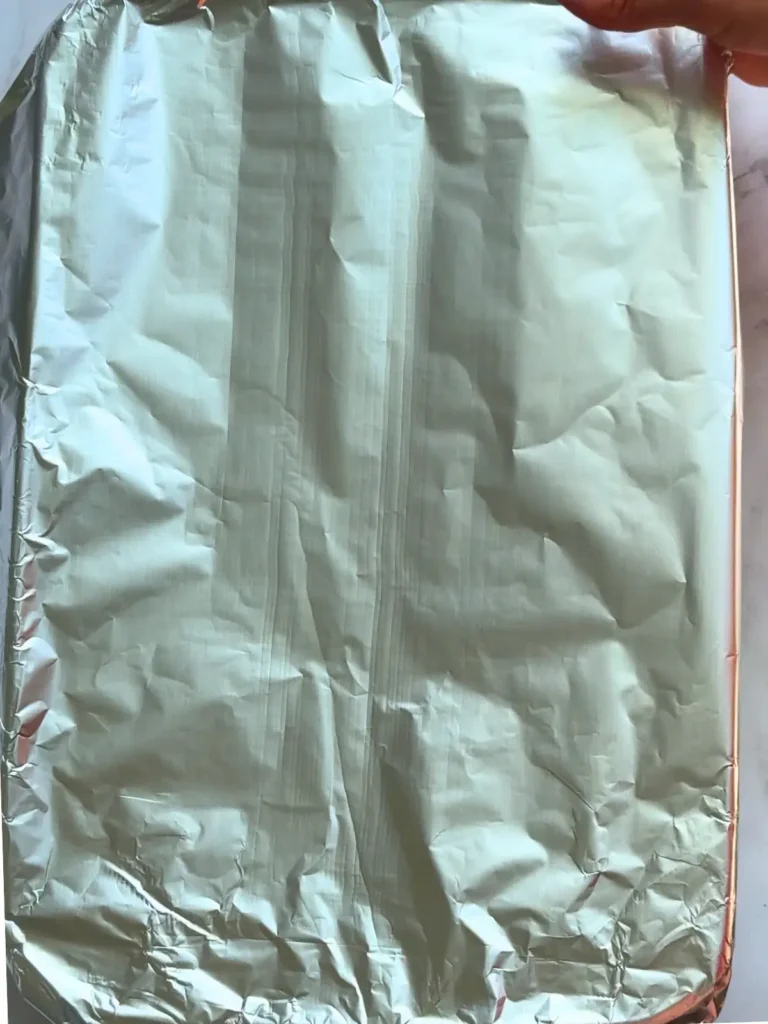 The fully assembled casserole covered in aluminum foil prior to baking.