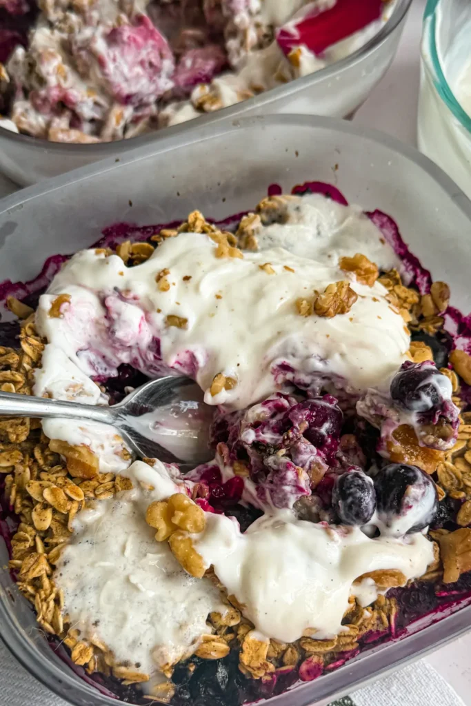A close-up of a spoon digging into the mixed berry cobbler. 