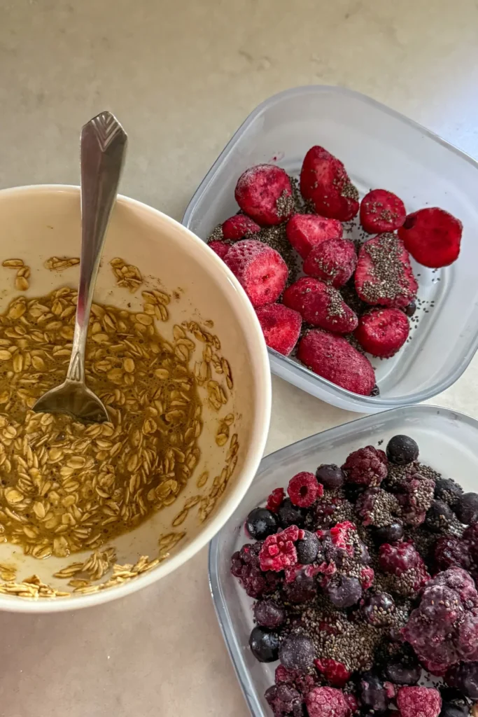 Two glass containers with fruit and chia seeds next to a bowl with the oat topping.