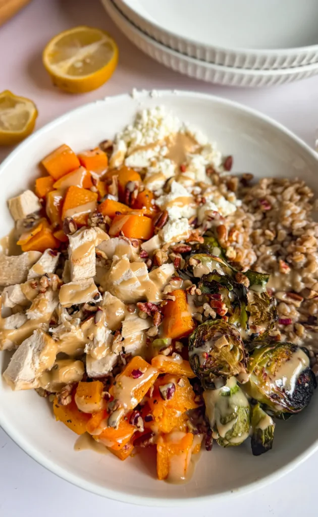 A roasted butternut squash and Brussel sprout bowl over farro with a maple tahini drizzle.