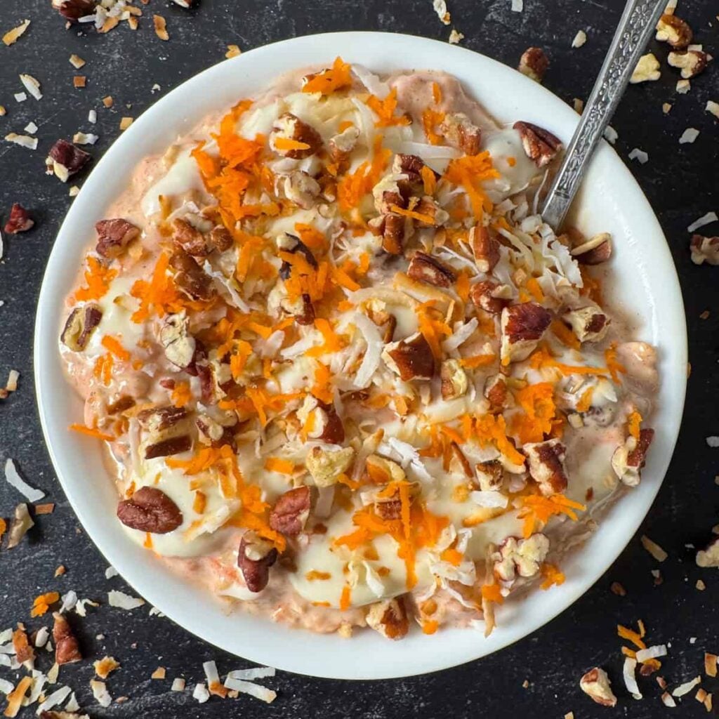 A birds-eye view of high calorie carrot cake overnight oats in a bowl on a table.