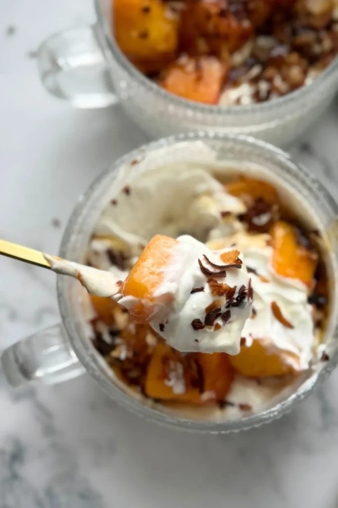 A close-up of a large spoonful of mango yogurt over a bowl of the mango cheesecake yogurt. 