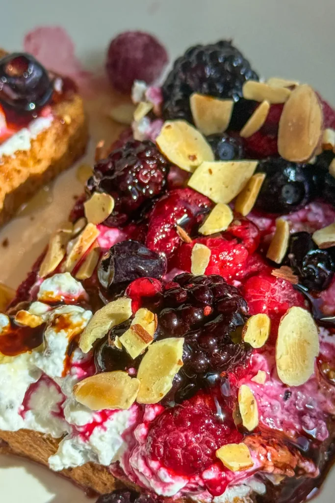 Creamy whipped cottage cheese toast topped with berries, slivered almonds and balsamic glaze.