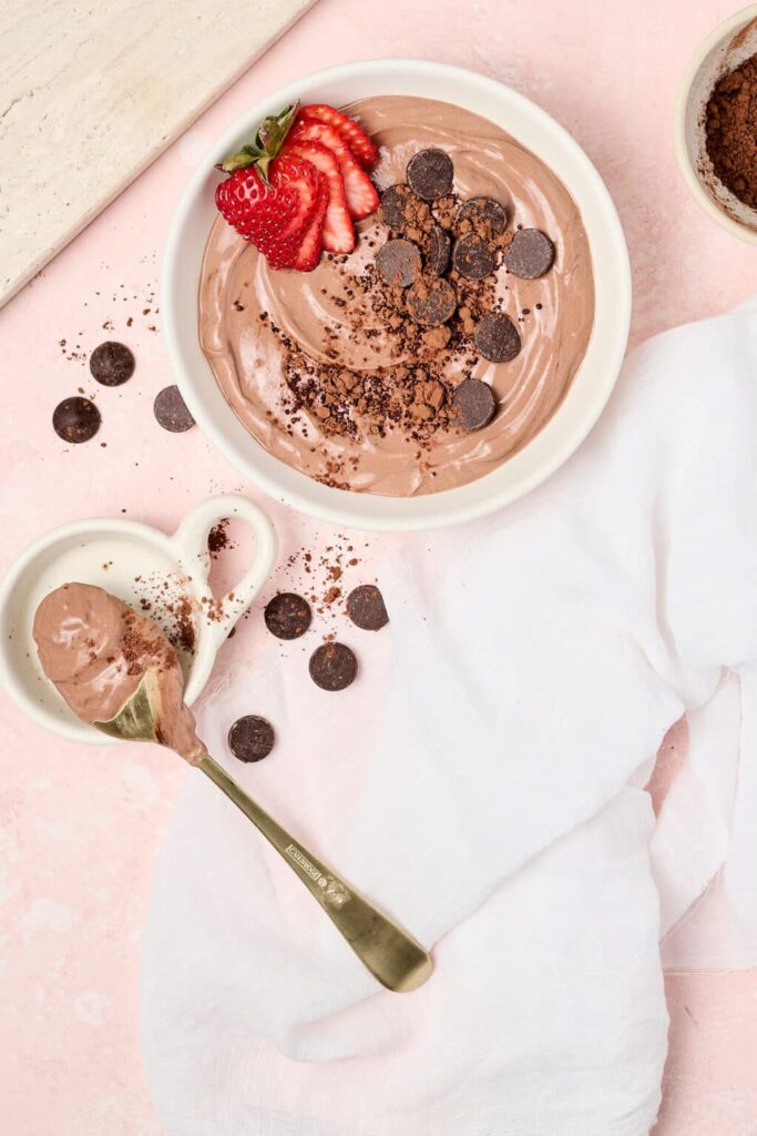 A big bowl of brownie batter dip topped with dark chocolate chips on a counter.