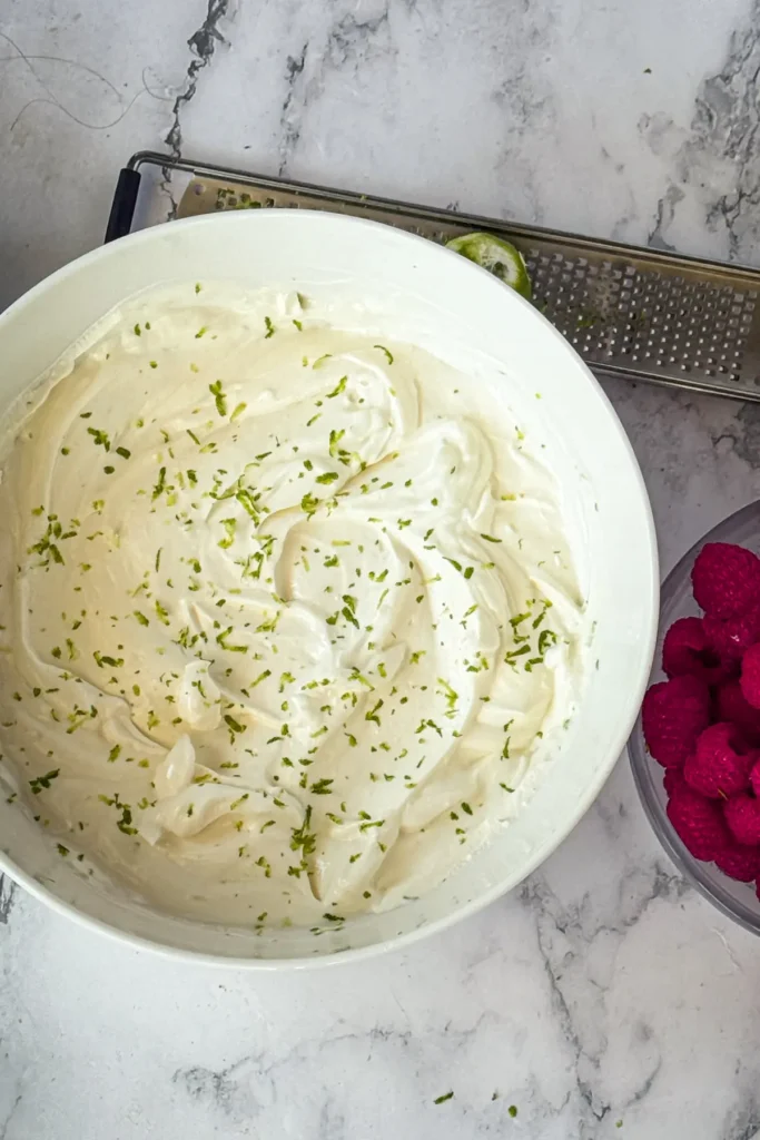 A birds-eye view of a the Greek yogurt dip after blending topped with lime zest in a big bowl.