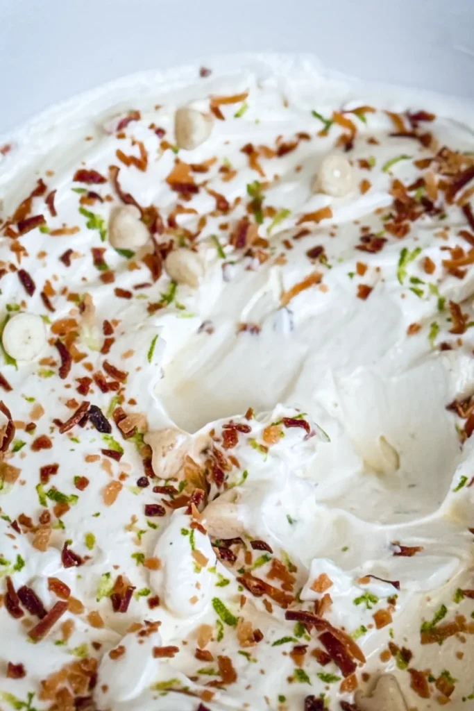 A close-up of the Greek yogurt dip with all the toppings on it with a spot that has been dug into.