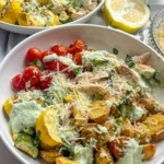 Two fully assembled parmesan basil chicken bowls on a table next to lemon wedges.