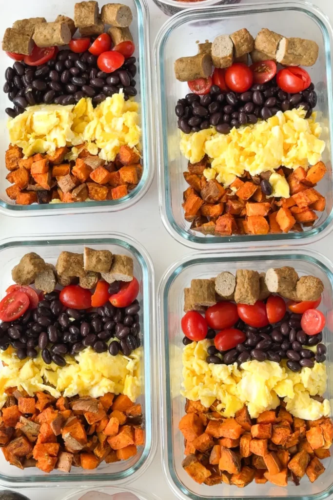 A birds-eye view of four meal prep containers fully assembled just without the shredded cheese.