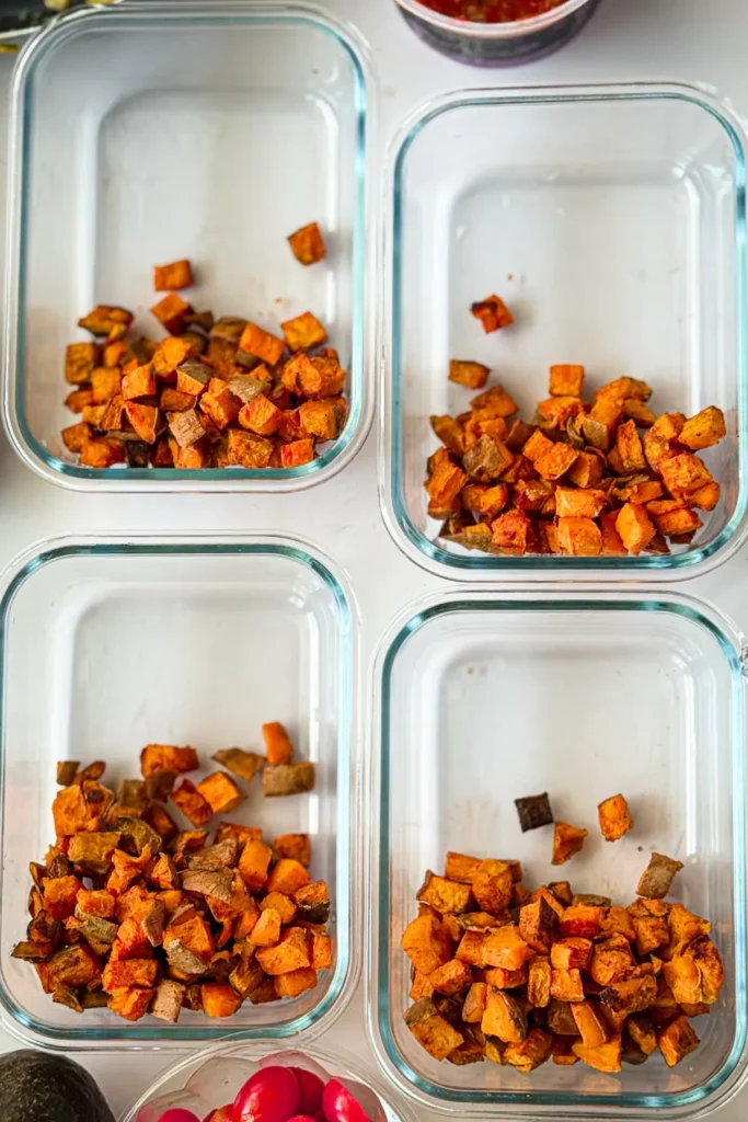 Four empty meal prep glass containers with roasted potatoes in each one.