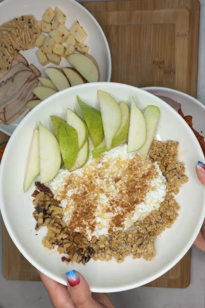 Someone holding up a cottage cheese pear plate with other snack plates in the background.